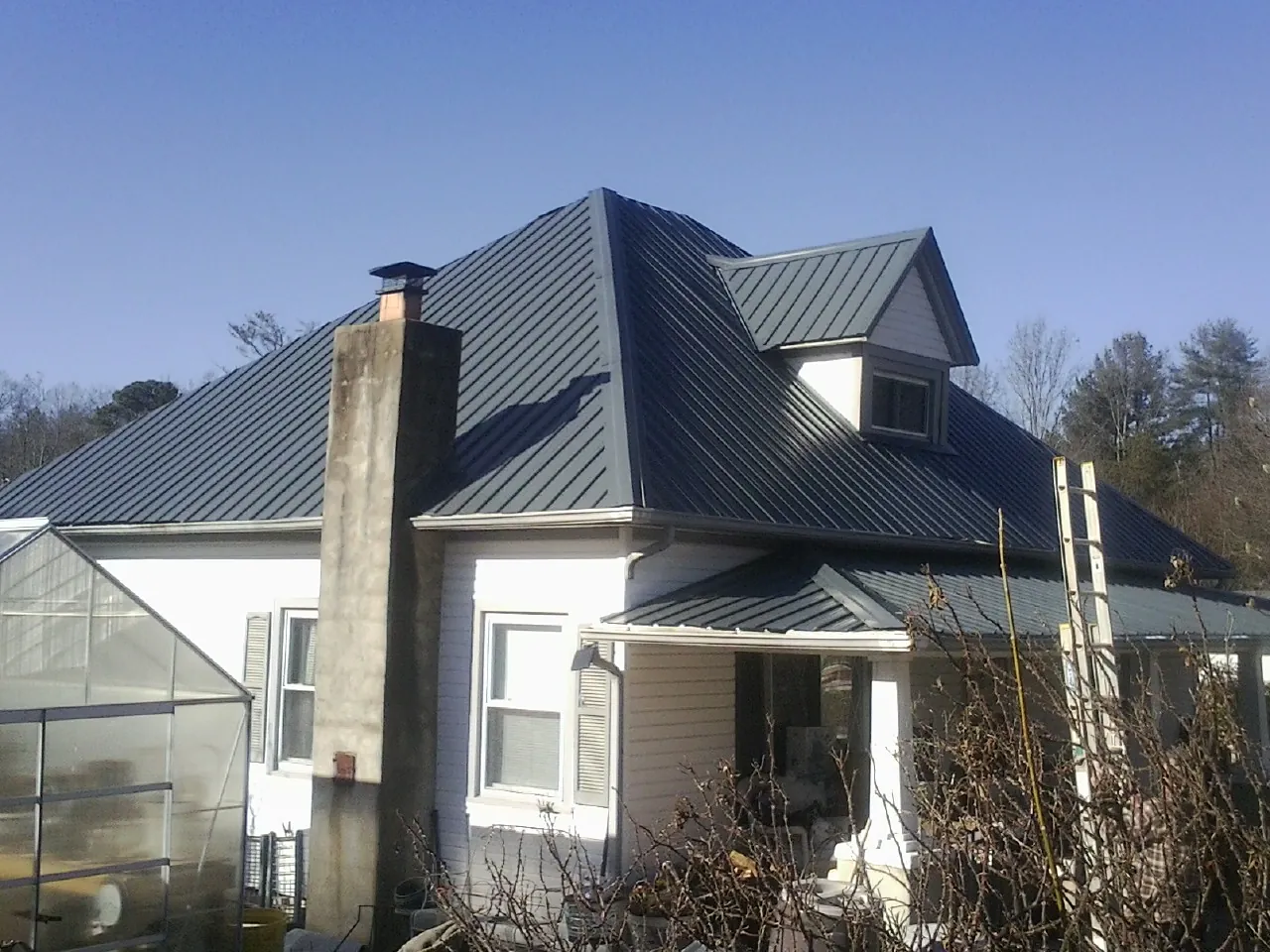 Dark blue standing seam metal roof on a white farmhouse with dormer — Slate & Tile Roof Repair by Roofing Brothers in Red Lion