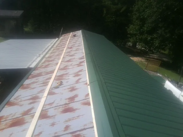 Old rusted panels beside newly installed green metal roofing — Wind Damage Roof Repair by Roofing Brothers in Red Lion