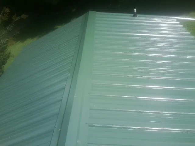 New green metal panels meeting at the ridge of a roof — Flat Roof Repair work by our crew in Red Lion