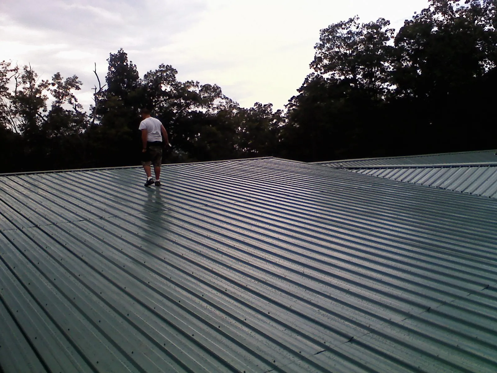 Roofer walking a wide expanse of new green metal roofing in Red Lion