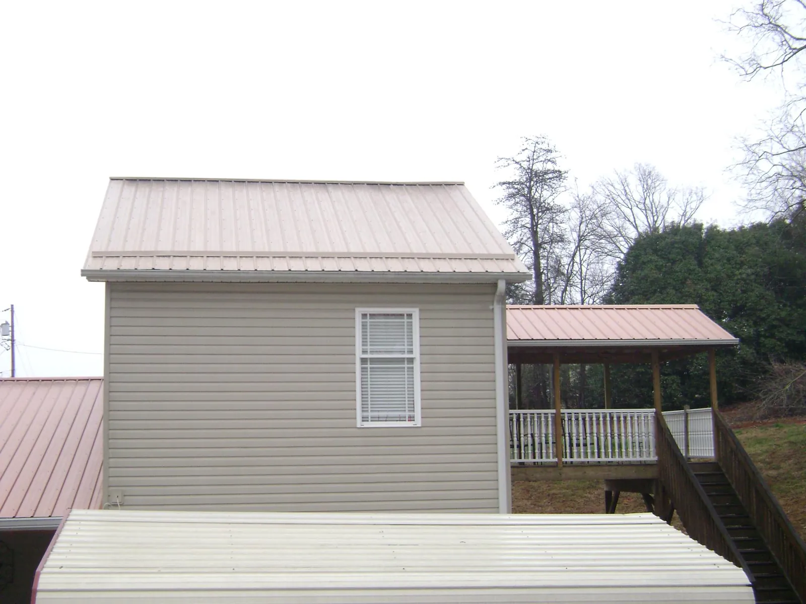 Tan metal roofs on a two story addition and attached porch, from a Roof Replacement job in Red Lion