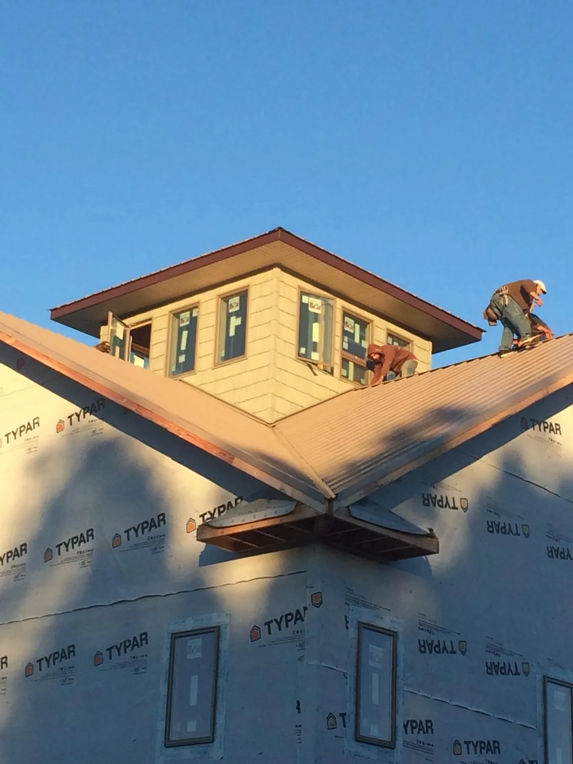 Roofers working around a rooftop cupola on a new metal roof at sunset — Roof Waterproofing in Red Lion by Roofing Brothers